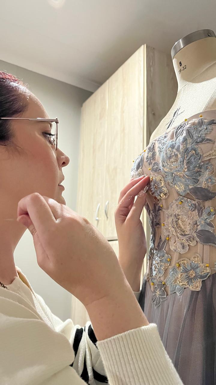 Lorrinda Richter hand-pinning a floral beaded gown in her atelier